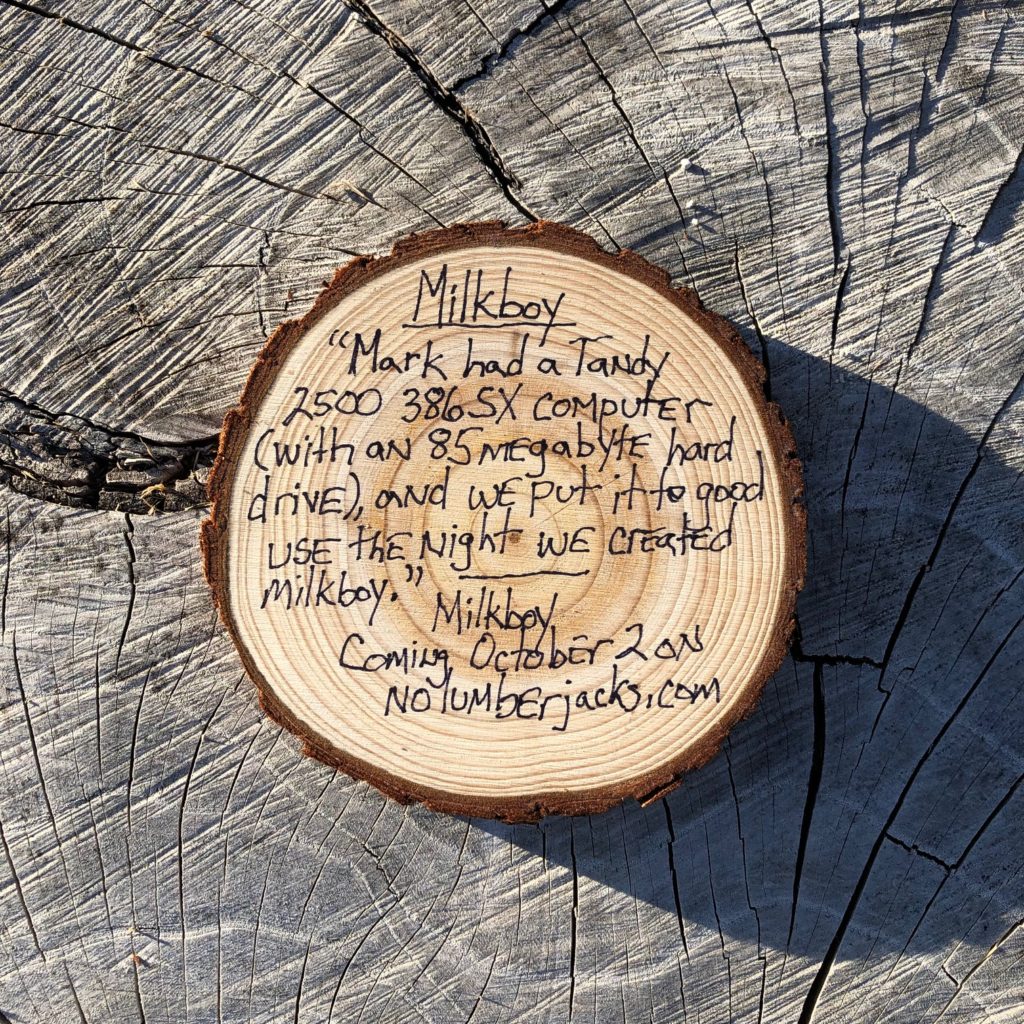A cross section of a 4-inch thick tree is placed on a full-sized tree stump. Written on the small round of tree: "Milkboy. "Mark had a Tandy 2500 386 SX computer (with an 85 megabyte hard drive), and we put it to good use the night we created Milkboy."
Milkboy
Coming October 2 on
nolumberjacks.com